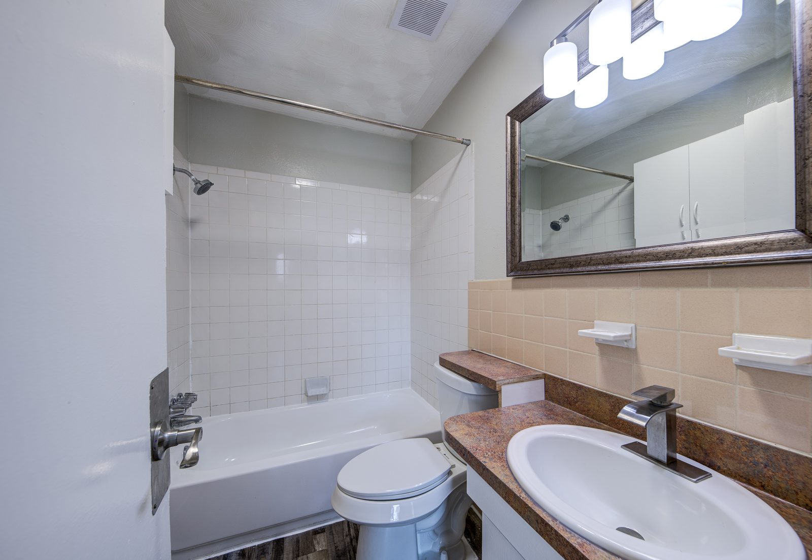 Bathroom with a tub and shower, a framed mirror and a vanity