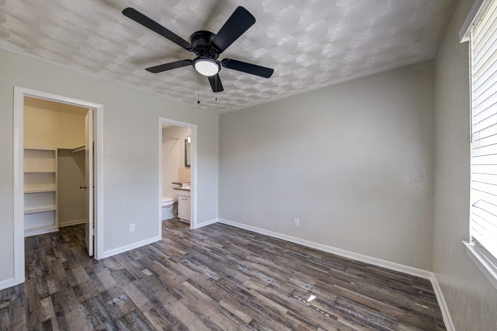 Bedroom with a ceiling fan, a walk-in closet and the bathroom door