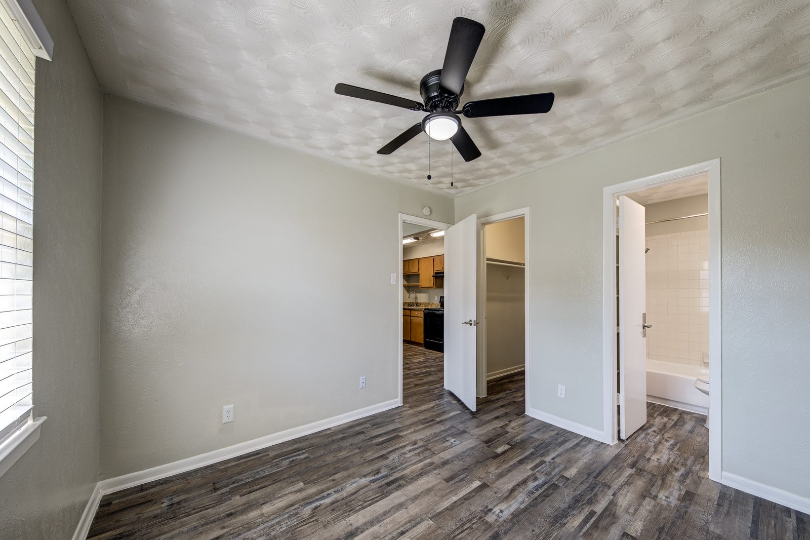 Bedroom with a ceiling fan and doors to the closet and the living room