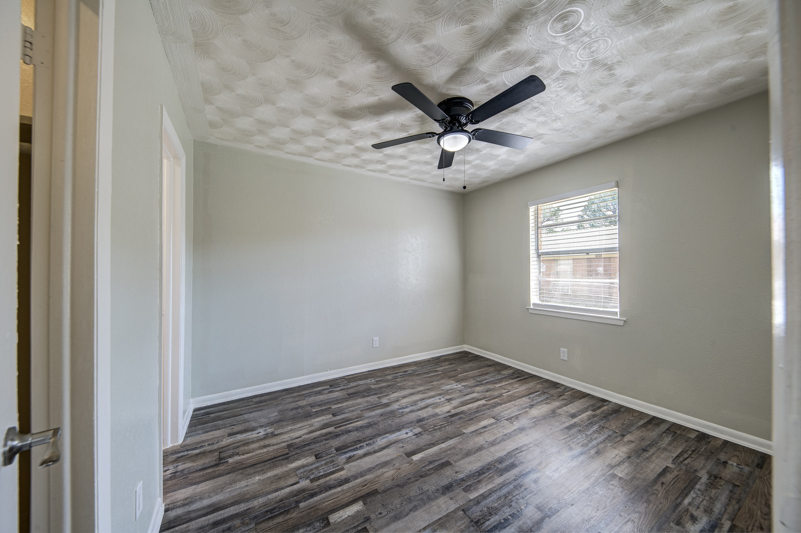 Bedroom with a ceiling fan, a window and grey vinyl plank floors