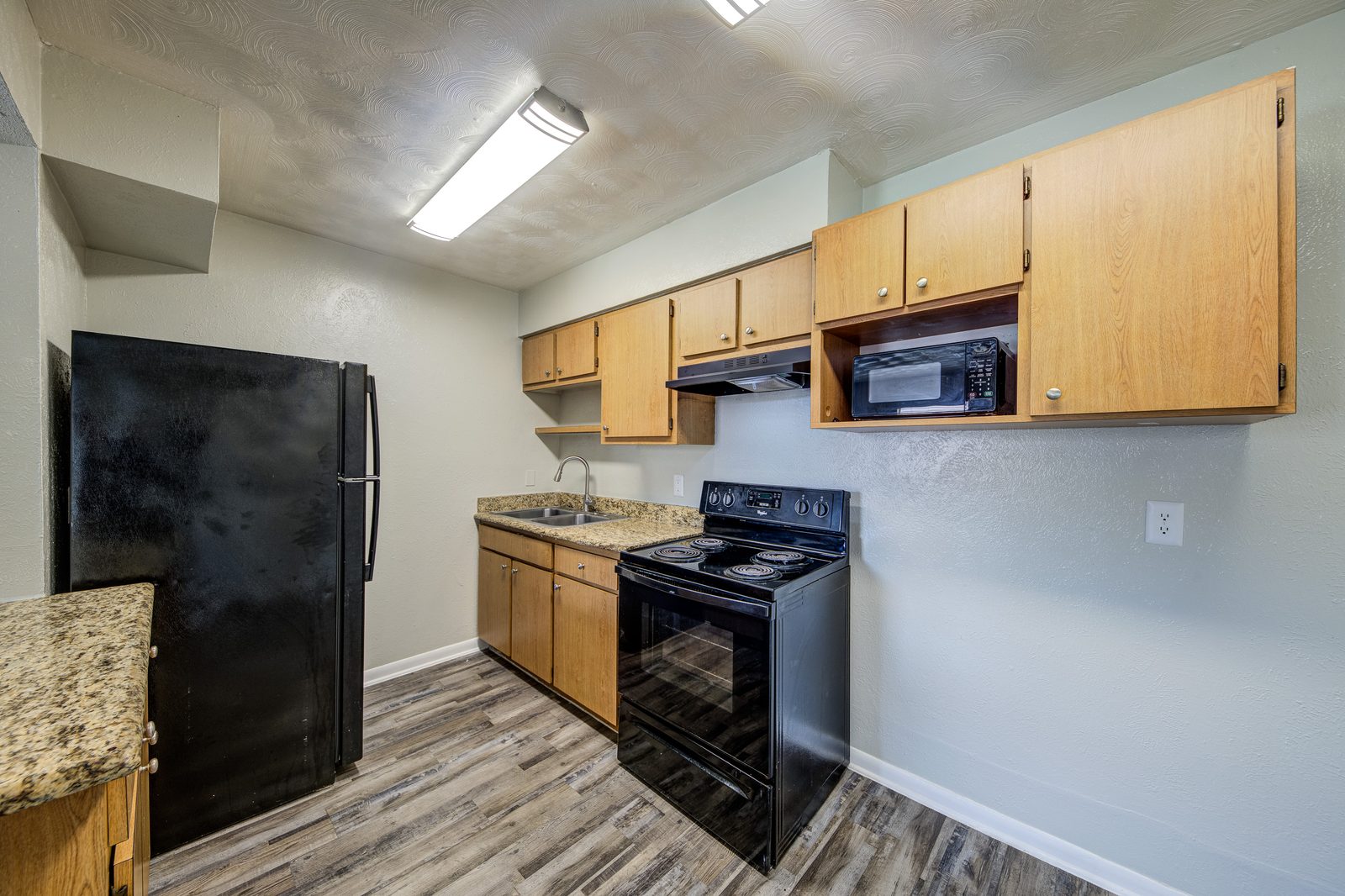 Kitchen with a black refrigerator, a black range and granite counters