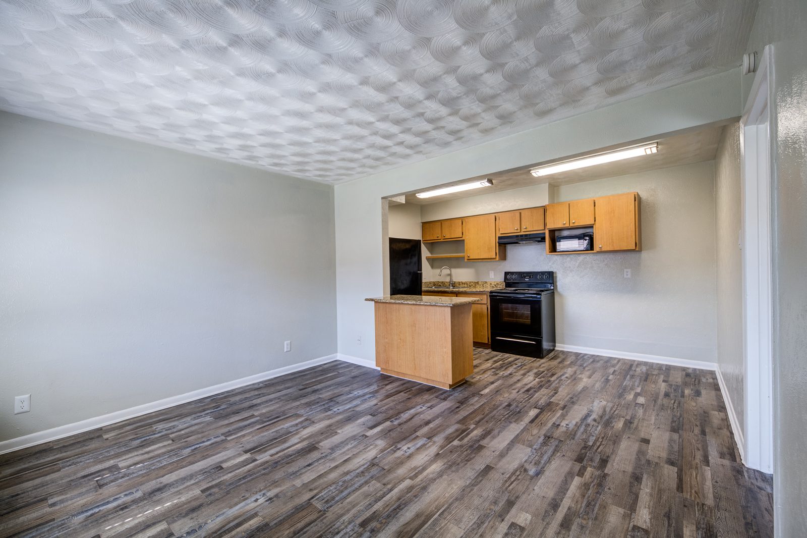 Living room with grey vinyl plank floors and an open kitchen