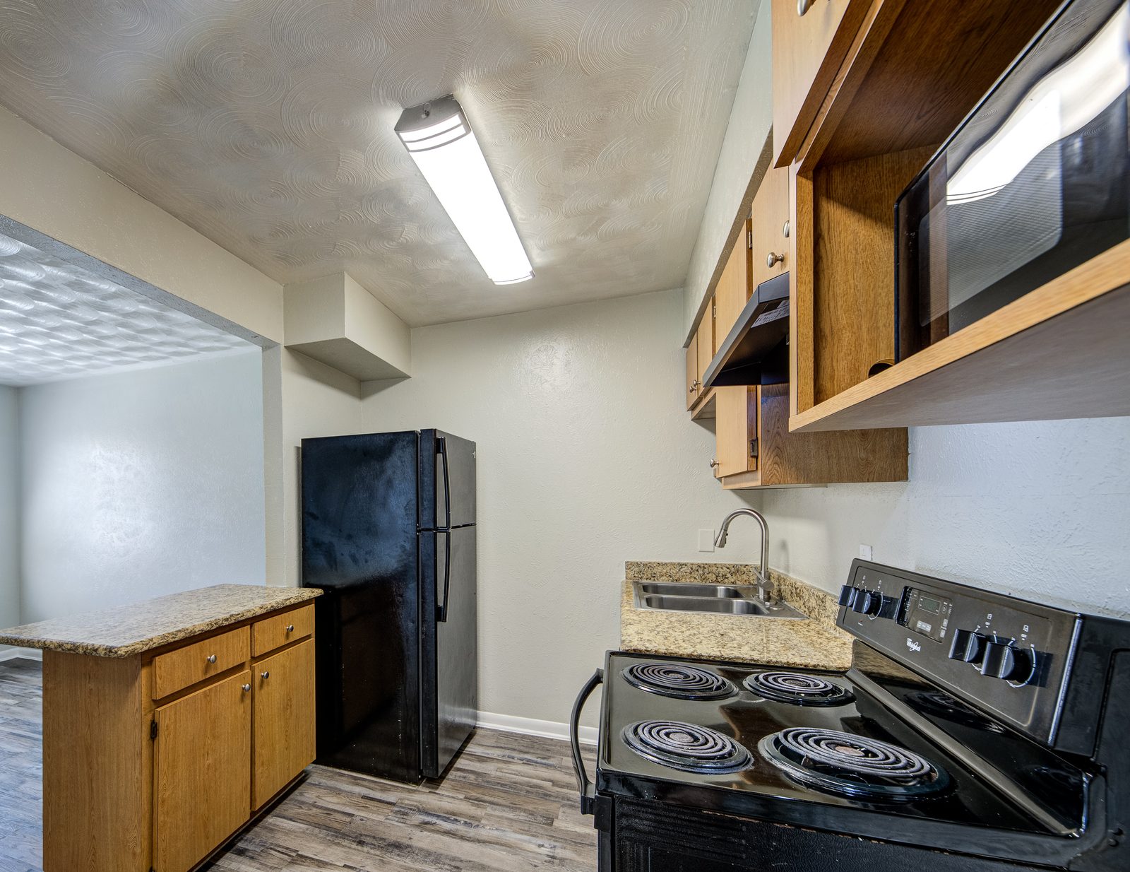 Kitchen with granite counters, a black range and a microwave above it