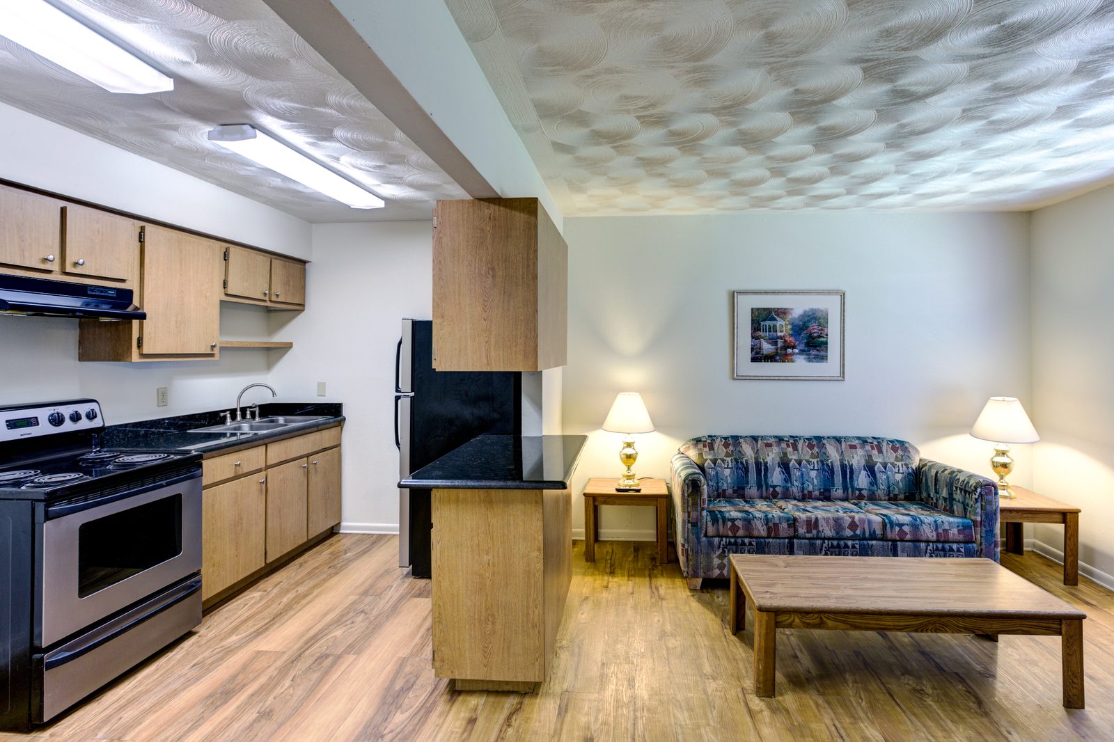 Furnished White Oak living room with an open kitchen and stainless appliances