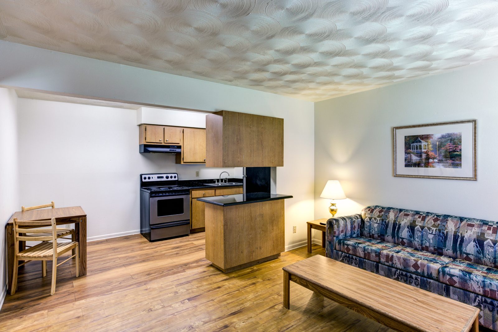Furnished White Oak living room with a dining table and the kitchen behind it