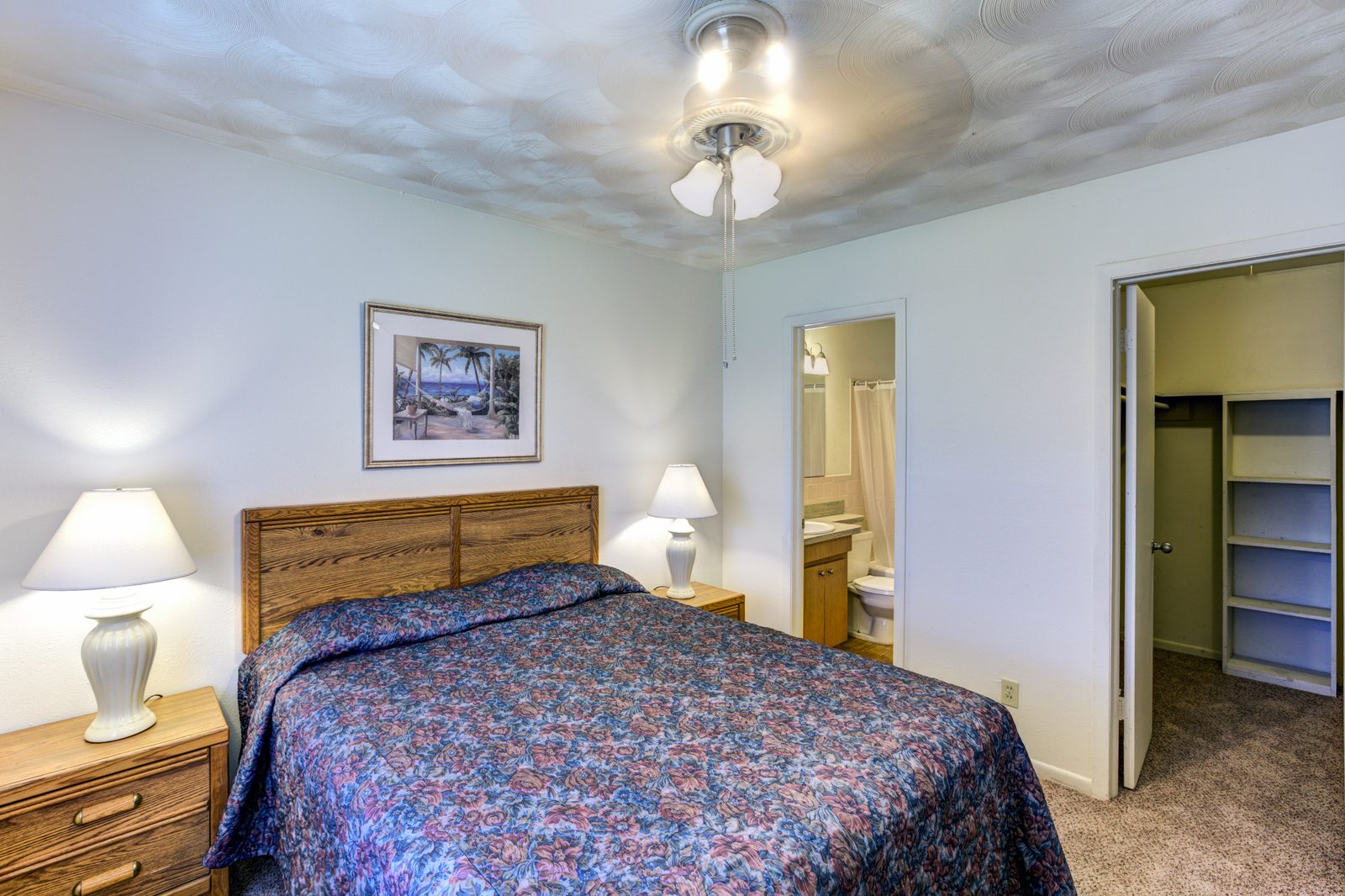 Furnished White Oak bedroom with a bed, two lamps and a walk-in closet